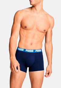 Marineblaue Boxer-Slips mit einem hellblauen elastischen Bund, der das "PUMA"-Logo zeigt. Hergestellt aus einem weichen, dehnbaren Stoff.