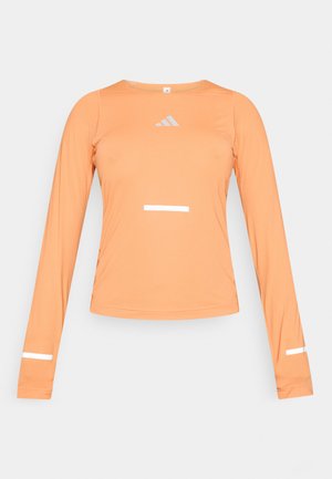 Maglia sportiva a maniche lunghe in tessuto arancione chiaro, con dettagli riflettenti bianchi sul petto e sulle maniche, con scollo rotondo e design aderente.