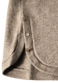 Beige strikstof med rundede kanter, sideknaplukninger og en tekstureret overflade. Blød og glat tekstur med en let glans.