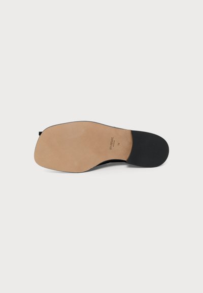 Semelle d'une chaussure en cuir avec un avant beige et un talon noir, taille 38, présentée sur un fond blanc uni.
