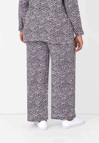 Černo-bíle vzorovaný outfit s volnými širokými kalhotami a dlouhým topem. Látka je měkká s hladkým povrchem a minimálními ozdobami.