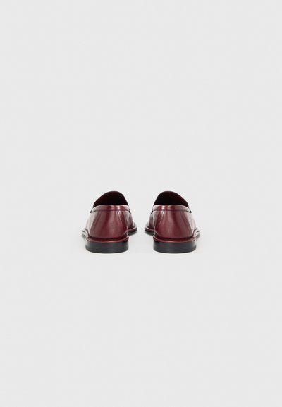 Μπορντό δερμάτινα loafers με ομαλή υφή, χαμηλό προφίλ και ελάχιστες ραφές. Μαύρες λαστιχένιες σόλες με ελαφριά γυαλάδα.