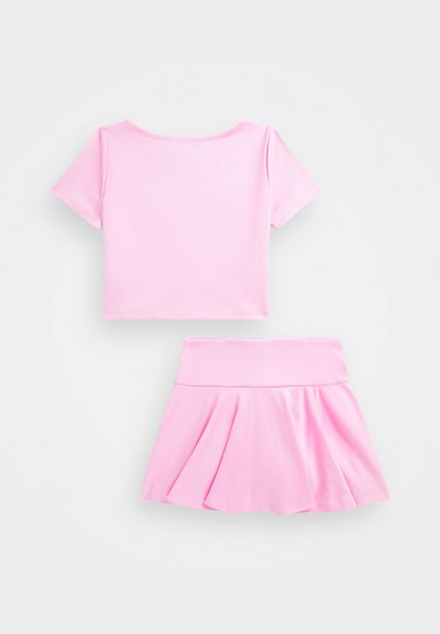 Roza skrajšana majica s kratkimi rokavi in okruglim izrezom, v kombinaciji z ujemajočo se nabranimi krilom z širokim pasom. Gladka tekstura.