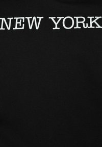 Felpa nera in cotone con audace scritta bianca "NEW YORK" sulla parte anteriore. Tessuto liscio e design con collo rotondo.