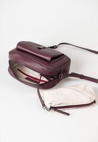 Leder-Crossbody-Tasche in tiefem Burgunderrot mit strukturiertem Äußeren, Klappe an der Oberseite und Innenfach mit Reißverschluss. Enthält eine hellfarbige, gemusterte Tasche.