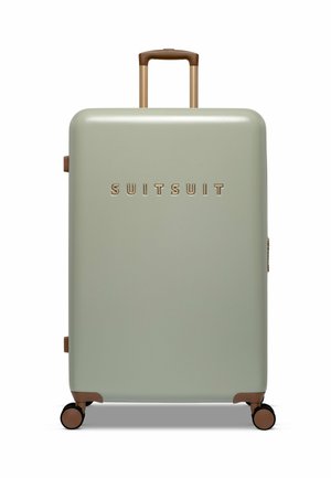 Hard-shell suitcase in soft green, featuring a smooth texture, gold logo, brown handle, and accents. Set on four black wheels for mobility.
