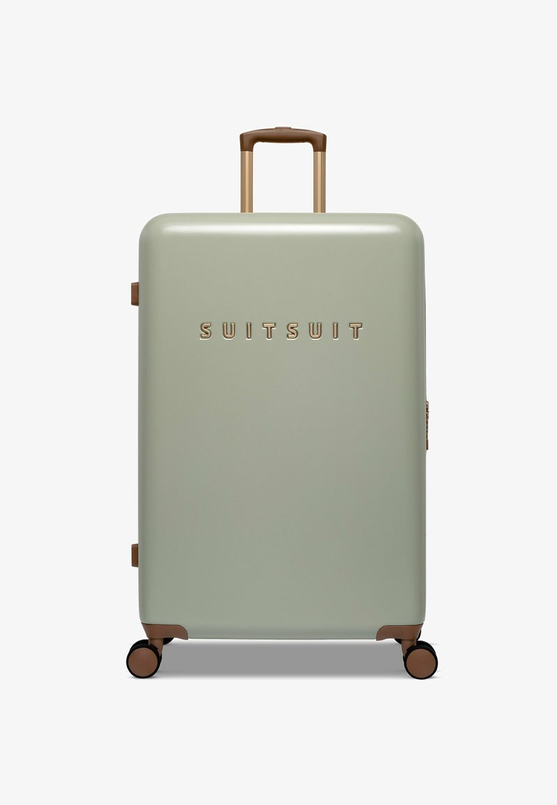 Harde koffer in zacht groen, met een gladde textuur, gouden logo, bruine handvat en accenten. Geplaatst op vier zwarte wielen voor mobiliteit.