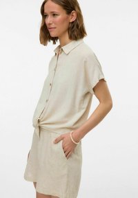 Beige linnedr vestido med bånd foran, korte ærmer og knaplukning. Med en afslappet pasform og sidelommer.