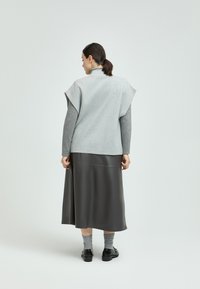 Gray wool top with cap sleeves over a gray long-sleeve shirt, paired with a dark gray leather skirt and gray socks. Black shoes.