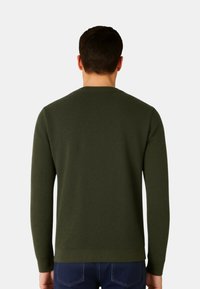 Maglione verde scuro realizzato in tessuto lavorato a maglia strutturata, con scollo rotondo e polsini e orlo a coste, visto da dietro.