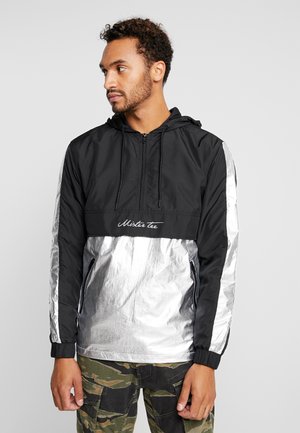 Schwarz und silberne Kapuzenwindjacke mit cropped Design, elastischen Bündchen und Reißverschlusstaschen. Logo auf der Vorderseite.