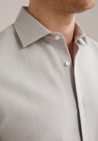 Camicia grigia chiaro con colletto standard. Presenta un tessuto strutturato e bottoni perlati. Vista ravvicinata del collo e del colletto.