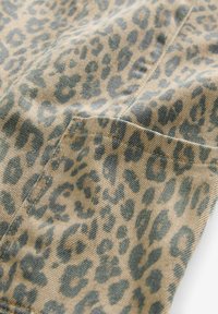 Tela de estampado de leopardo en beige y verde apagado. Presenta una superficie texturizada con manchas distintivas y un detalle de bolsillo cosido.