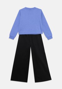 Blauer Pullover mit langen Ärmeln und runder Ausschnitt, kombiniert mit lockeren, weit geschnittenen schwarzen Hosen. Beide Teile haben eine glatte Textur.