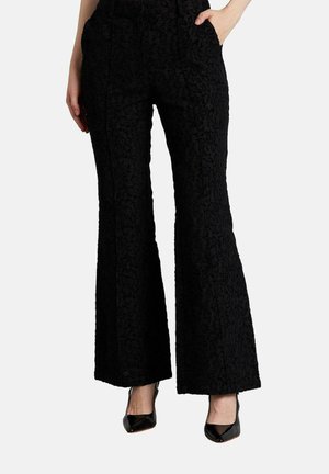 Pantalones negros acampanados con un patrón floral texturizado, que presentan una cintura alta y dos bolsillos frontales. Combinados con tacones negros para un contraste.