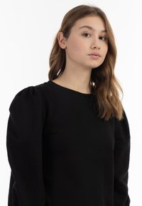 Czarny sweatshirt z bufkowymi rękawami, okrągłym dekoltem i gładką teksturą. Posiada dopasowane ciało i odzwierciedla elegancki, minimalistyczny styl.