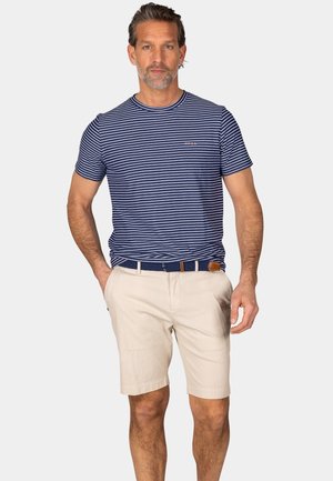 Marineblauwe en witte gestreepte korte mouwen shirt gecombineerd met beige shorts. De shorts hebben een gemêleerd patroon en worden geaccentueerd met een blauwe riem.