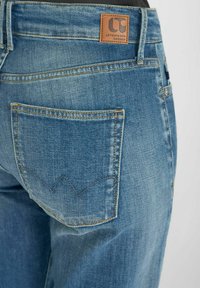 Blauwe denim jeans met een leren merklabel, contrasterende stiksels en een achterzak met een golvend ontwerp. Klassieke pasvorm, medium wassingen.