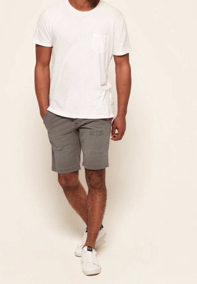 T-shirt en coton blanc avec une poche poitrine, associée à un short gris avec des détails cousus. Complété par des baskets blanches.