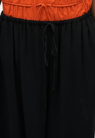 Mustad lahtised püksid elastse vöörihma ja ees kena naerdtisega, kantud oranži voltimisega topiga.