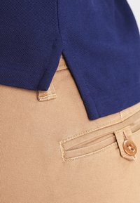 Marinblå polo med texturerad tyg, instoppad i khaki chinos med knappficka och mjukt, elastiskt material.
