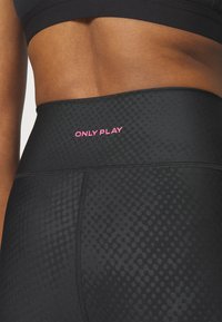Black leggings with a textured pattern, featuring a high waistband and a prominent pink "ONLY PLAY" logo. Smooth fabric finish.