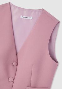Gilet senza maniche di colore rosa con una trama di tessuto liscia, caratterizzato da due bottoni rotondi, una scollatura a V e una tasca frontale. Etichetta del marchio visibile.