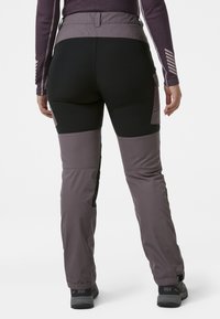 Pantalones de alto rendimiento para exteriores en gris y negro bicolor, con una cinturilla ajustada, rodillas articuladas y puños ajustables.