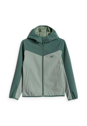 Chłopiec stoi, ubrany w zieloną kurtkę na zamek, białą koszulkę, szare spodnie dresowe oraz szaro-białe buty sportowe na neutralnym tle.