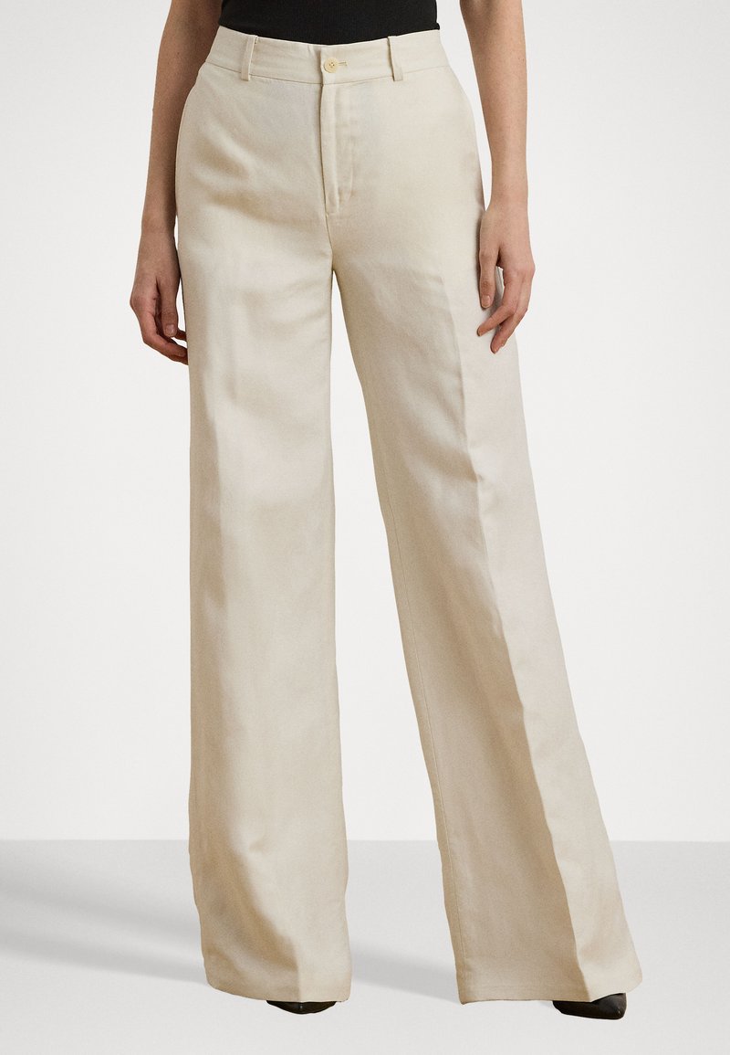 Pantalons larges en tissu beige clair, dotés d'une taille haute, d'un léger éclat, d'une fermeture par bouton sur le devant et de poches latérales. Texture lisse.
