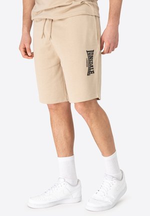 Beezid puuvillase shortsid, millel on nööriga vöö ja must logo "Lonsdale London" vasakul jalal. Kombineeritud valgete tossude ja sokkidega.