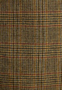 Wollstoff in einem Karomuster mit warmen Farbtönen in Gelb, Braun und Grün, durchzogen von feinen roten und blauen Streifen.