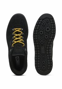 Zwarte suède sneakers met gele veters, met een gestructureerde zwarte zool met ronde patronen en een reliëflogo op de tong en de inlegzool.