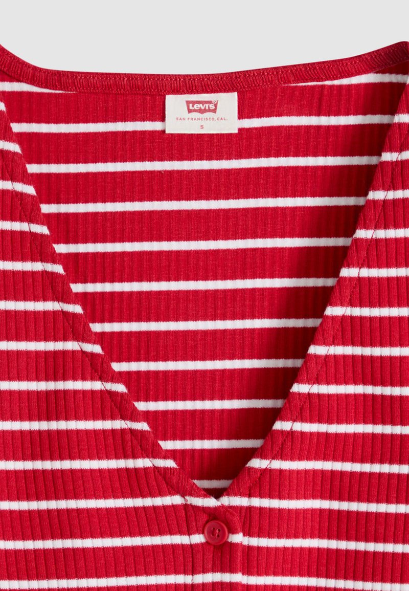 Chemise côtelée à rayures horizontales rouges et blanches avec col en V et petit bouton rouge sous l'encolure, étiquette Levi's indiquant la taille petite.