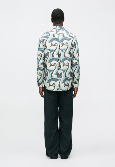 Tričko s dlhým rukávom so potlačou labute v pastelových farbách. Bavlnený materiál, s golierom, s detailmi na gombíky. Kombinované s tmavými džínsovými nohavicami.