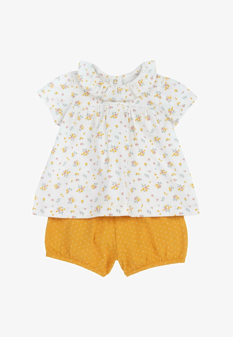 Haut à manches courtes à motif floral blanc avec col à volants ; associé à un short jaune à pois. Tissu doux, design décontracté.