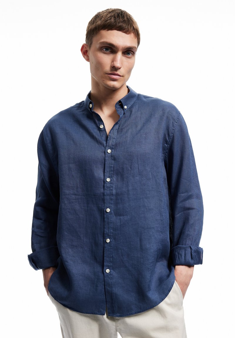 Blauwe button-up shirt van een lichte stof, met een spread collar, lange mouwen en een ontspannen pasvorm. Gladde textuur, eenvoudige knoopdetails.