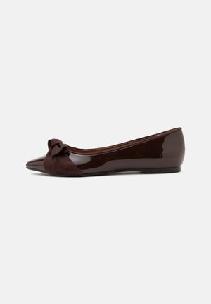 Chaussure plate en cuir verni marron foncé avec bout pointu et détail nœud en tissu sur le dessus, montrée de profil sur un fond uni.