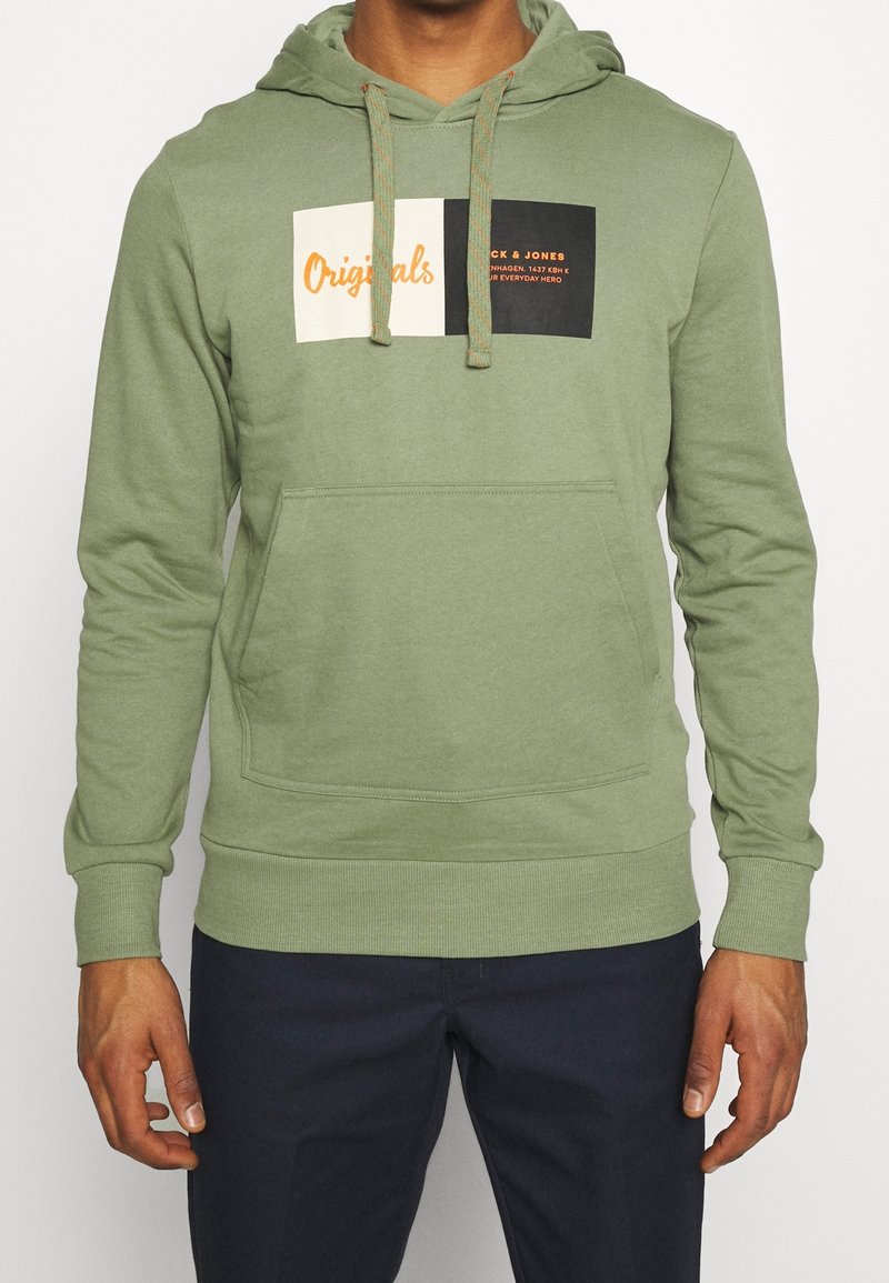 Felpa verde in cotone con tasca a marsupio frontale, cappuccio regolabile con cordoncino e design a blocchi di colore che presenta elementi testuali.