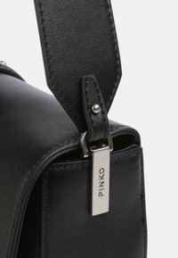 Borsa in pelle nera con una texture liscia, dotata di un'etichetta metallica con la scritta "PINKO" e di una tracolla robusta con dettagli di cucitura.