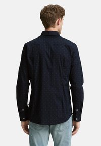 Marineblaues Hemd mit kleinen, hellblauen Punkten, langen Ärmeln und Knopfmanschetten. Verfügt über einen klassischen Kragen und eine lockere Passform.