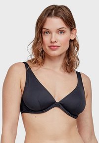 Reggiseno nero con una finitura in tessuto liscio, design a scollo a V profondo, spalline larghe e una cucitura vicino al centro. Nessun hardware o decorazione visibile.