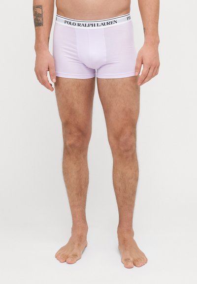 Un modèle masculin portant des boxers en coton violet clair avec une ceinture noire contrastante arborant le logo "POLO RALPH LAUREN".