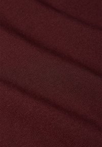 Burgundy tyg med en jämn textur, med ett subtilt ribbat mönster och en jämn väv, vikt i mjuka vågor. Inga framträdande detaljer eller hårdvara.