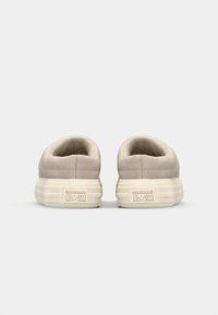 Beige lavsneakers med overdel i ruskind, blødt for og gummisål. Har prægede logoer på hælen og et afdæmpet, minimalistisk design.