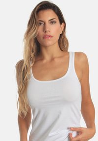 White tank top with a fitted design, made of smooth cotton fabric. Features wide shoulder straps and a rounded neckline.