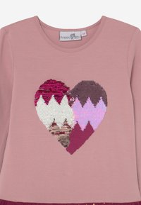 Růžová košile s dlouhými rukávy, která má design srdce z flitrů v odstínech bordó, bílé a růžové s texturovaným povrchem a kulatým výstřihem.