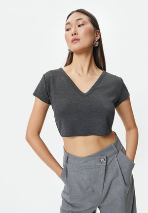 Kulkulsort cropped t-shirt med V-hals og korte ærmer, lavet af blødt stof, kombineret med lysegrå high-waisted bukser.