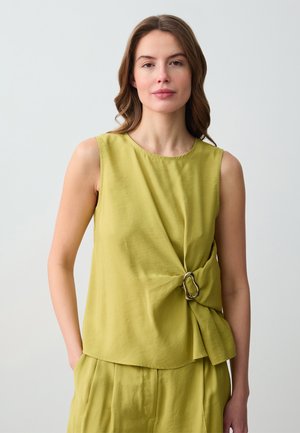Top senza maniche verde con un design intrecciato e dettagli in metallo argentato. Tessuto liscio; vestibilità comoda. Abbinato a pantaloni coordinati.