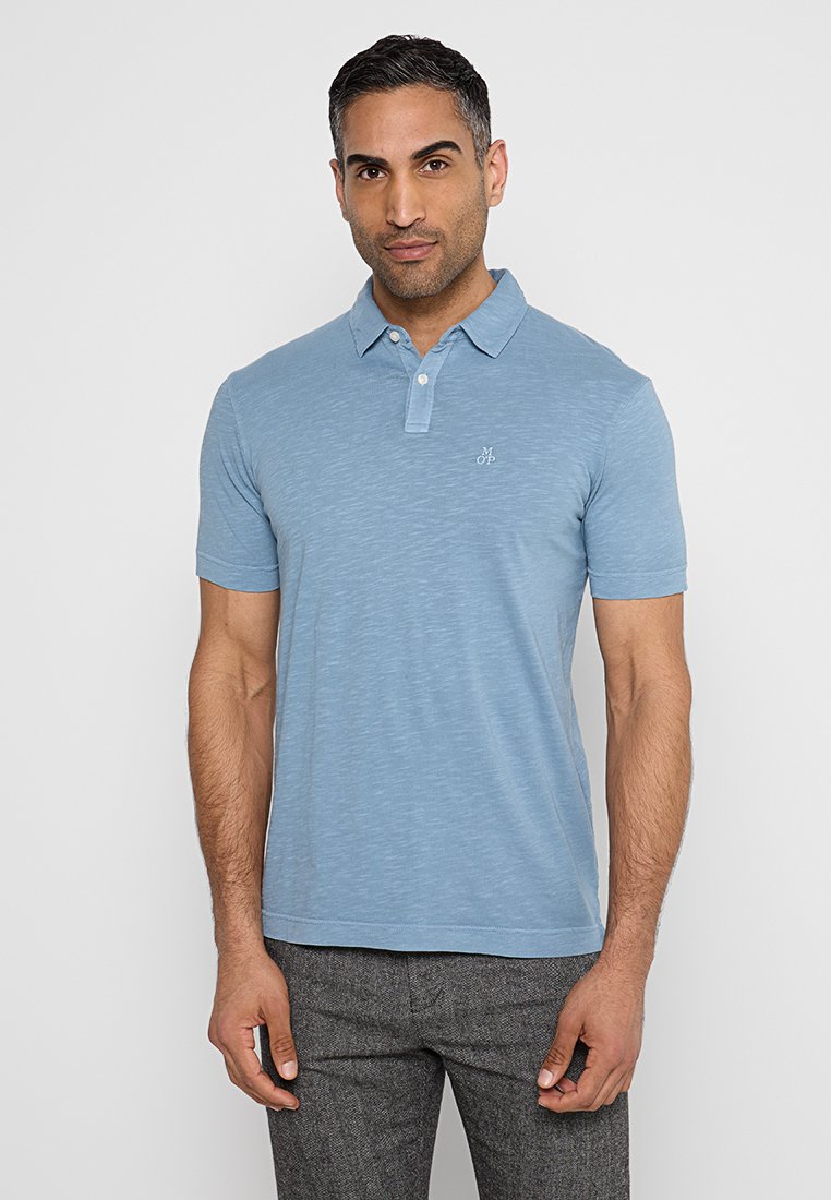 Hellblaues Polohemd aus einem weichen, strukturierten Stoff; verfügt über eine Knopfleiste mit zwei Knöpfen und ein kleines gesticktes Logo auf der Brust.